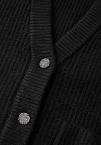 Svart cardigan med ribbad textur, djup V-hals och tre dekorativa metallknappar med texturerad yta.