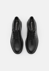Chaussures en cuir noir avec une texture lisse, présentant un design classique à lacets et de subtils détails de couture, taille 37.
