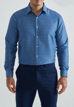 chemise bleu à manches longues avec un petit motif floral, en coton, boutonnée à l'avant, et col classique, assortie à un pantalon bleu marine.