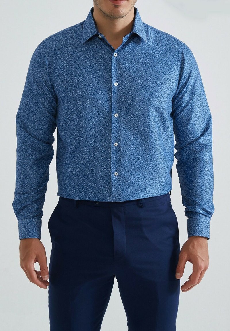 chemise bleu à manches longues avec un petit motif floral, en coton, boutonnée à l'avant, et col classique, assortie à un pantalon bleu marine.