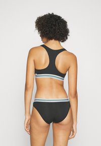 Fekete bikini szett versenyháttal. Zöld, fehér és kék csíkos elasztikus pántok a melltartón és a bugyin. Sima textúra.