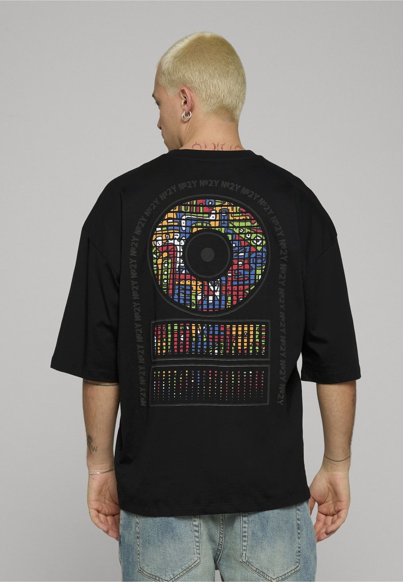 Černé oversized tričko s barevným abstraktním grafickým motivem na zádech, zobrazující kruhové a obdélníkové vzory.