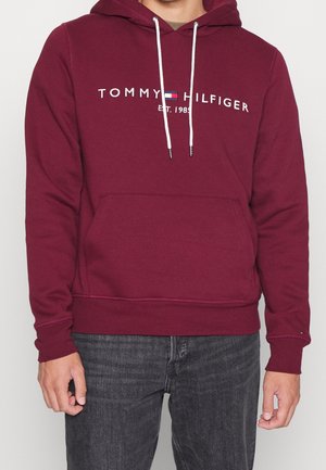 Sudadera granate hecha de una mezcla de algodón, con un bolsillo frontal, cordones blancos y texto del logo en el pecho.