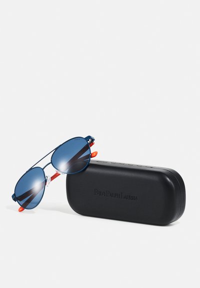 Óculos de sol com lentes em gradiente azul e armação azul-marinho, apresentando detalhes em vermelho. Acompanha uma capa protetora preta com o logotipo da marca em relevo.