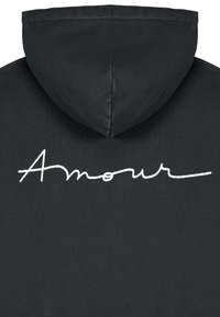 Felpa nera con cappuccio caratterizzata da un ricamo testurizzato in corsivo bianco con la scritta "Amour" sul retro. Il tessuto appare morbido e consumato.