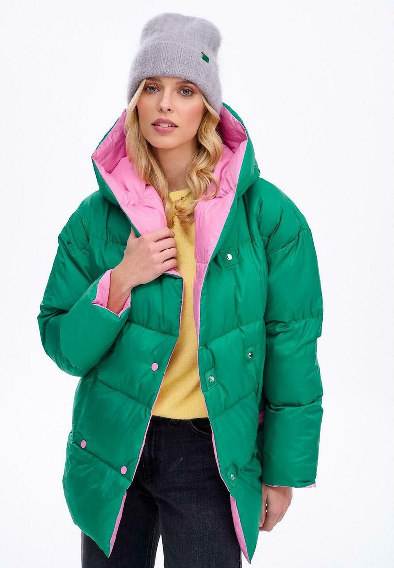 Zielona i różowa pikowana kurtka z kapturem, zapinana na zatrzaski, wykonana z błyszczącego materiału. Do tego szary dziany beret i żółta bluzka.