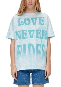 Lichtblauwe oversized t-shirt met "LOVE NEVER FADES" in vet turquoise lettertype, met een zacht tie-dye patroon en korte mouwen.