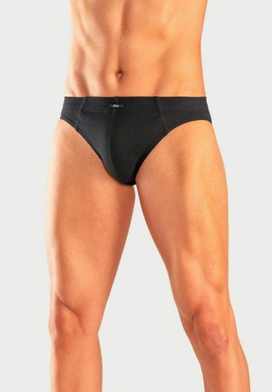 Torse et jambes masculins portant un slip noir sur fond clair, montrant une peau tonique et des cuisses musclées.