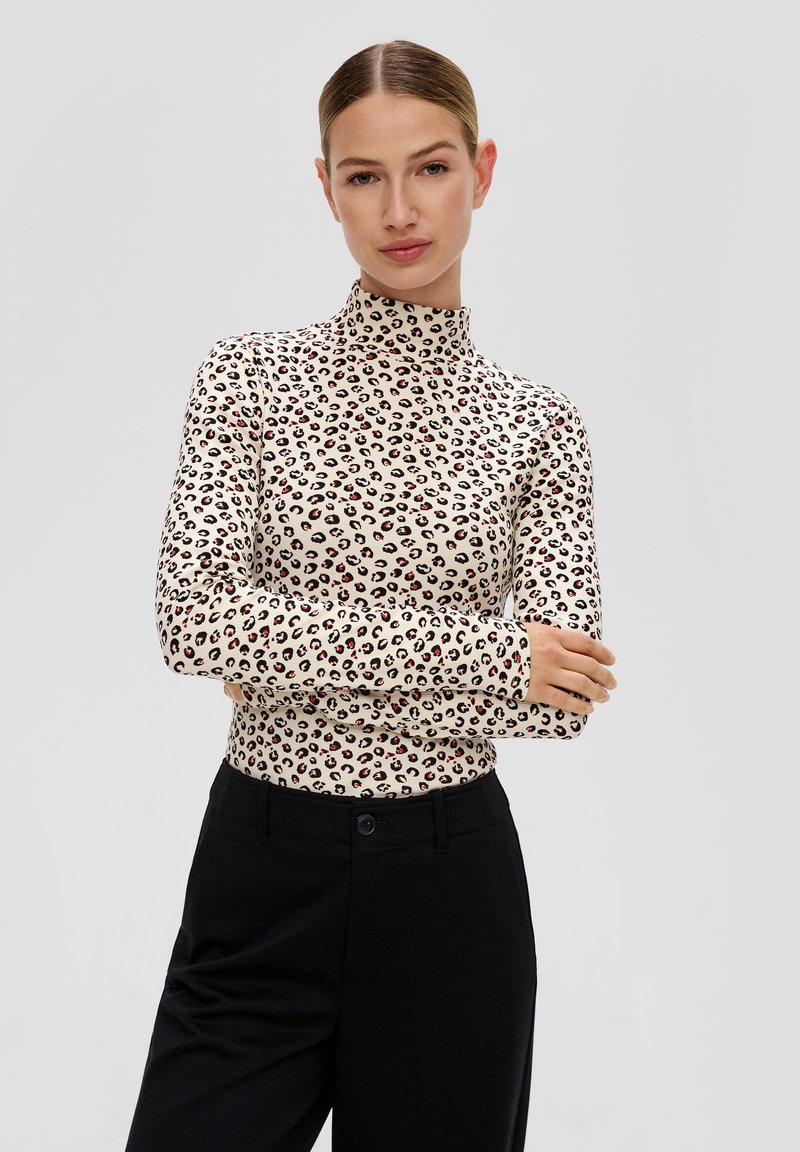 Kremowy golf w panterkę z czarnymi i czerwonymi akcentami. Długie rękawy, dopasowany krój, gładki materiał. W połączeniu z czarnymi spodniami.