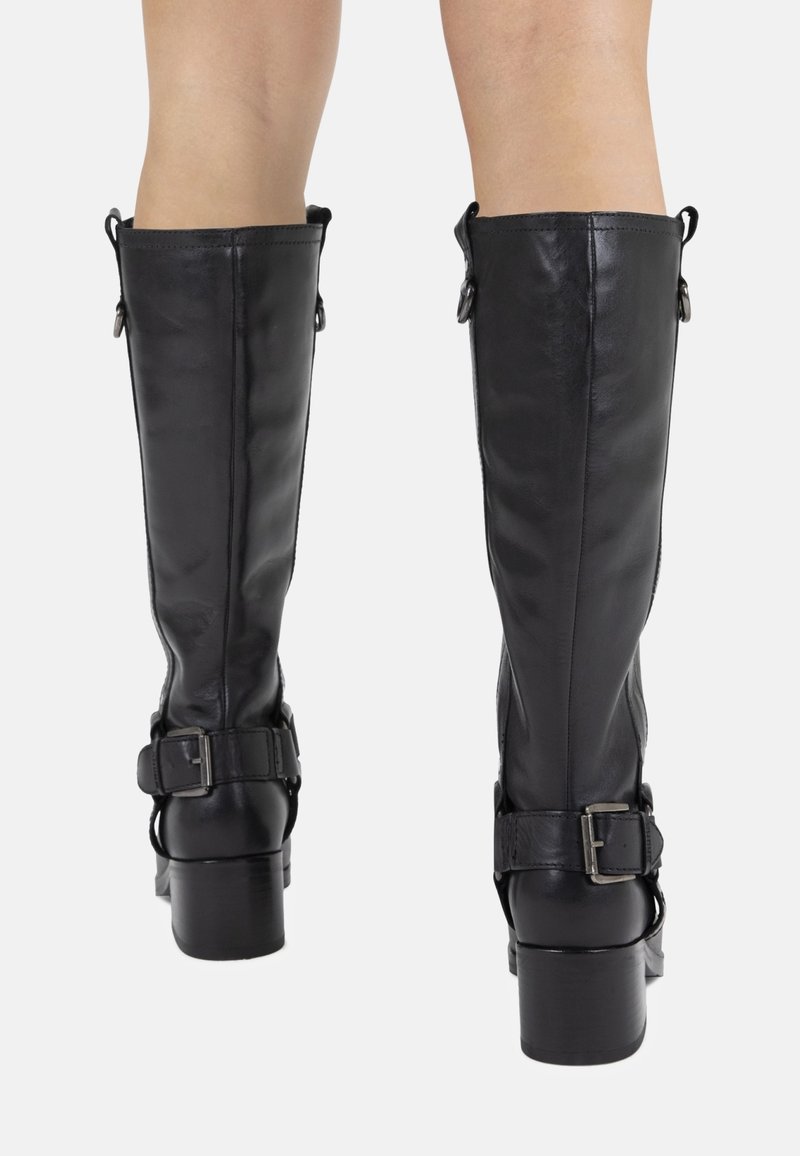 Bottes en cuir noir montantes, avec une finition lisse, présentant un large talon carré et des boucles réglables sur les côtés.