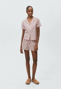 Set de pijamale cu mânecă scurtă în nuanțe de roz, cu un model floral, având un top lejer și şorturi asortate, confecționat dintr-un material ușor.