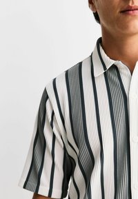 Short-sleeve shirt with a button-down collar, featuring vertical stripes in dark gray and white, textured fabric with ribbed detail.