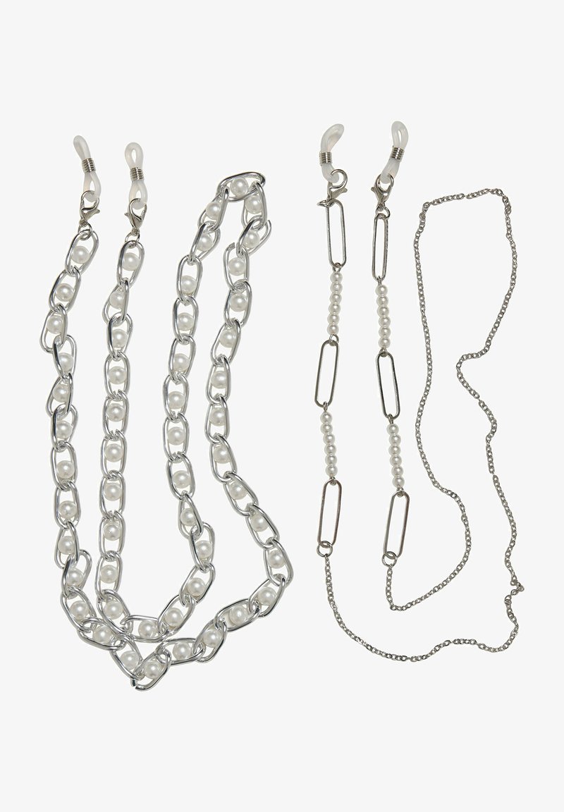 Štyri šperkové reťaze: jedna s veľkými striebornými článkami a bielymi korálkami, jedna s menšími článkami a bielymi perlami, a dve jednoduché strieborné reťaze.