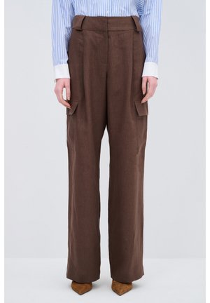 Braune, hoch taillierte Hose mit weitem Bein, ausgestattet mit Seitentaschen und einem glatten, strukturierten Stoff. Kombiniert mit spitzen, braunen Schuhen.