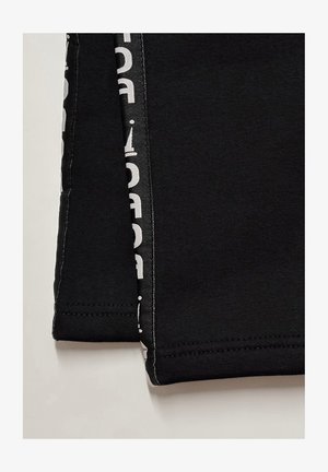 Black cotton pants with a smooth texture, featuring a white printed accent along the side and neatly stitched hems.