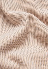 Teksturowana tkanina w miękkim beżowym kolorze, z wzorzystym splotem. Materiał wydaje się lekki i lekko elastyczny.