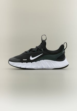 Sort og hvid Nike sportssko med mesh-overdel, hvid swoosh-logo, tyk polstret sål og trækflapper på tungens og hælens side.