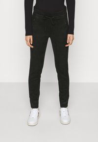 Mörkgrön träningsoverallsbyxor i ett mjukt material, med dragsko i midjan och dragkedjefickor fram. Smal passform med avsmalnande ben.