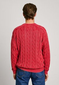 Roter kabelstrick Pullover mit Rundhalsausschnitt, gerippten Bündchen und Saum, ausgestattet mit strukturierten Mustern auf dem Rücken und Raglanärmeln.