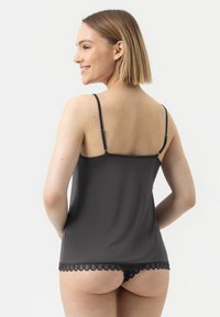 Black camisole with thin adjustable straps and lace trim at the hem. The fabric appears smooth and lightweight, offering a fitted silhouette.