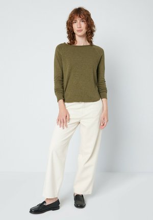 Oliven grøn langærmet top, cremefarvede vidde bukser og sorte loafers. Struktureret stof, afslappet pasform og minimalistisk design.