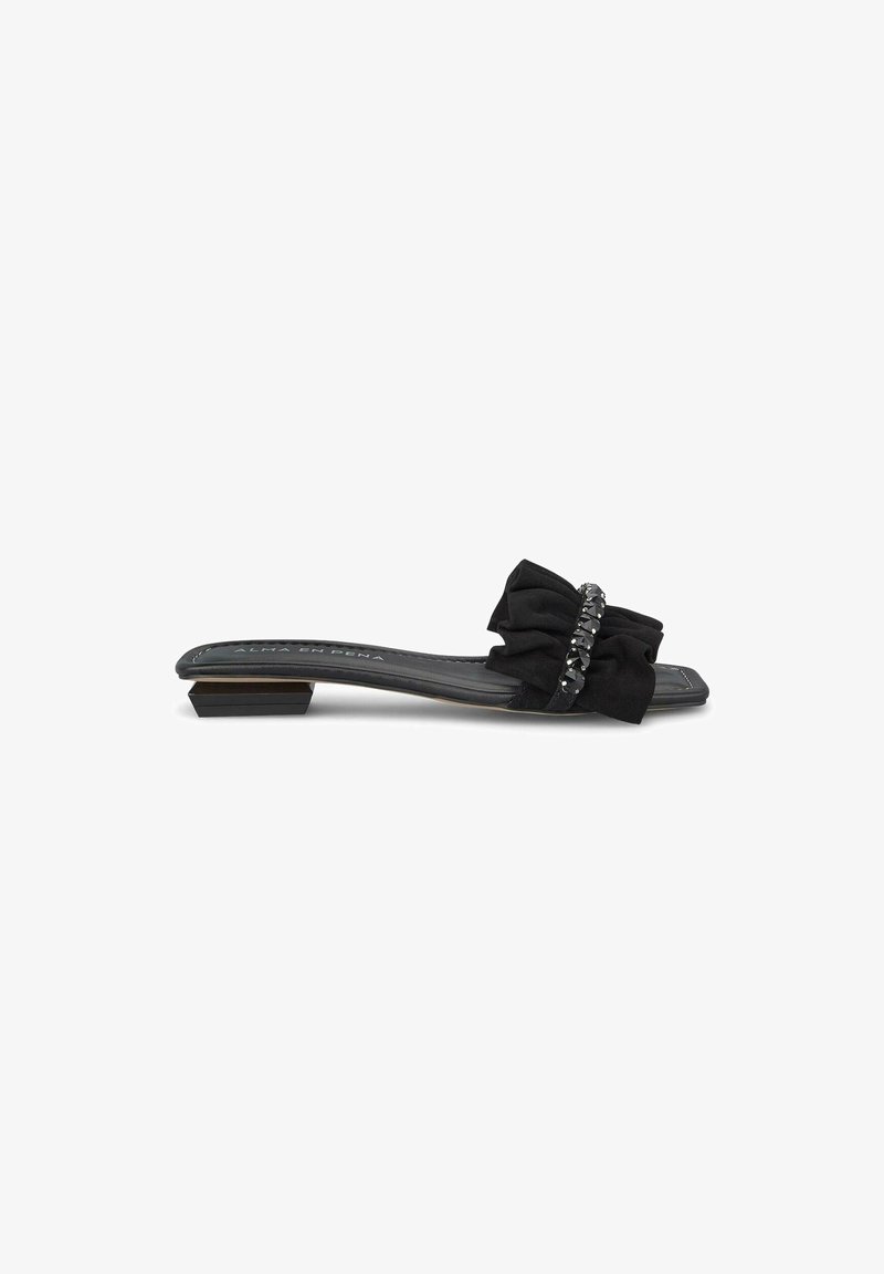 Černé skluzné sandály s texturovanou látkovou mašlí a korálkovým akcentem. Mají nízký čtvercový podpatek a hladkou vnitřní podšívku. Jednoduchý, elegantní design.