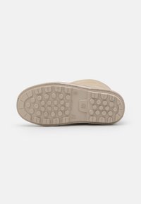Suela de goma beige con un agarre texturizado. Presenta lugs redondeados y una superficie plana, diseñada para ofrecer tracción y durabilidad.