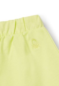 Tessuto verde chiaro con una consistenza morbida, caratterizzato da una cintura elastica e un piccolo logo in rilievo dello stesso colore.