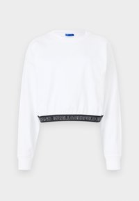 Witte geknipte sweatshirt met lange mouwen, ribbelmanchetten en een zwarte tailleband met de tekst "KARL LAGERFELD JEANS" in het wit. Soepele textuur.