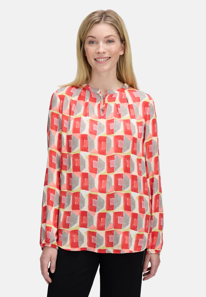 Langarmbluse aus leichtem Stoff mit einem mehrfarbigen geometrischen Muster in Rot, Grau und Gelb, rundem Ausschnitt und Falten.