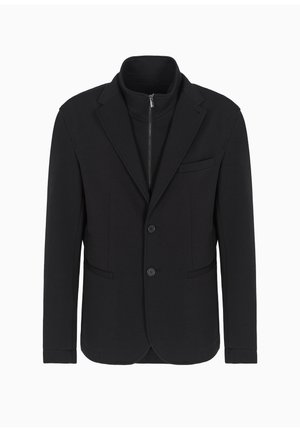 Blazer nero con colletto alto e chiusura con zip, presenta due tasche frontali, due bottoni e una superficie in tessuto liscia.