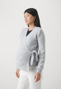 Cardigan drapé gris à côtes avec fermeture à lien, manches longues et texture douce, conçu pour les femmes enceintes.