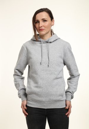 Felpa grigia con una texture morbida, corde di regolazione, e polsini e orlo a coste, indossata con jeans scuri su uno sfondo chiaro.