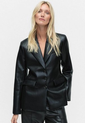 Svart läderblazer med en strukturerad design, snedskärda slag, dubbelknäppning och två framfickor. Slät textur.