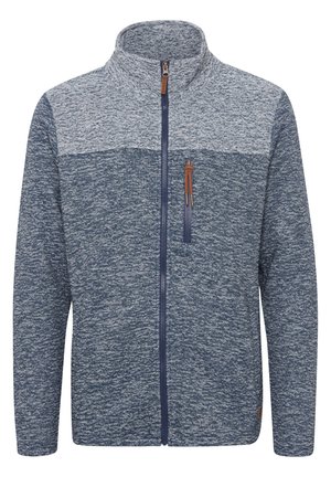 Fliisjakki, millel on heledat sinist värvi disain, kõrge krae, täispikk tõmblukk ja tõmbetasku rinnal, millel on pruun nahast aktsent.