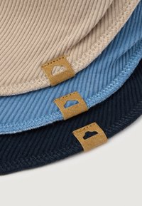 Tre tovagliette in tessuto rigato beige, azzurro chiaro e blu navy, con etichette in pelle beige con forme intagliate. Ogni tovaglietta presenta bordi cuciti.