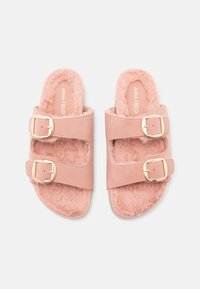 Sandale roz cu talpă plată, dotate cu două curele ajustabile, căptușeală din blană sintetică și catarame aurii. Textură moale pentru confort.