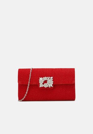 Roter Glitzer-Clutch mit silberner Blumen-Strass-Schließe und dünnem silbernem Kettenriemen auf einem einfachen hellen Hintergrund.
