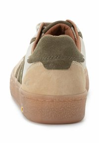 Sneaker dengan bagian atas suede berwarna coklat muda dan hijau zaitun, sol coklat muda bertekstur, kerah empuk, dan jahitan dekoratif di sepanjang sisi.