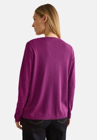 Pull violet à manches longues avec un col rond, fabriqué dans un matériau doux. Présente des poignets et un ourlet côtelés, une texture lisse et une coupe décontractée.
