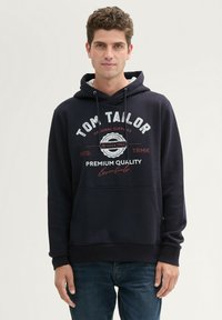 Felpa navy con logo e testo sul davanti, dotata di cappuccio con cordino, tasca a marsupio e polsini e orlo a costine.