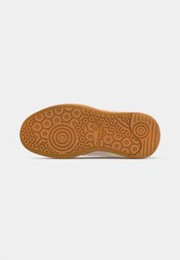Rubber shoe sole with a circular pattern. Color is light brown with textured detailing. Features a logo at the center.