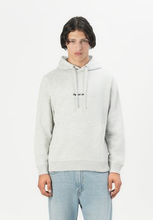 Grijze katoenen hoodie met een voorzak, trekkoorden en zwarte tekst op de borst. Gepaarde met lichtblauwe jeans. Eenvoudig, casual ontwerp.