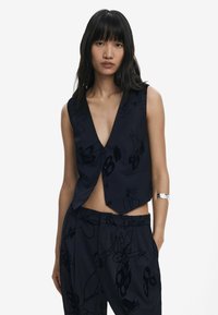 Navy sleeveless vest with a deep V-neck, featuring textured floral patterns and a fitted design. Paired with matching patterned trousers.