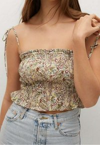 Top court à smocks à fleurs en crème avec des motifs verts et bordeaux, doté de fines bretelles réglables et d'un ourlet en étages.