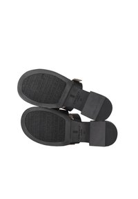 Zwarte sandalen met twee banden van glad materiaal, met een platte zool met doorgestoken "CRICKIT"-tekst en een ronde hak. Maat 37.