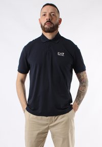 Polo navy de algodón con cuello, manga corta, tapeta de tres botones y logo de EA7 en el lado izquierdo del pecho.