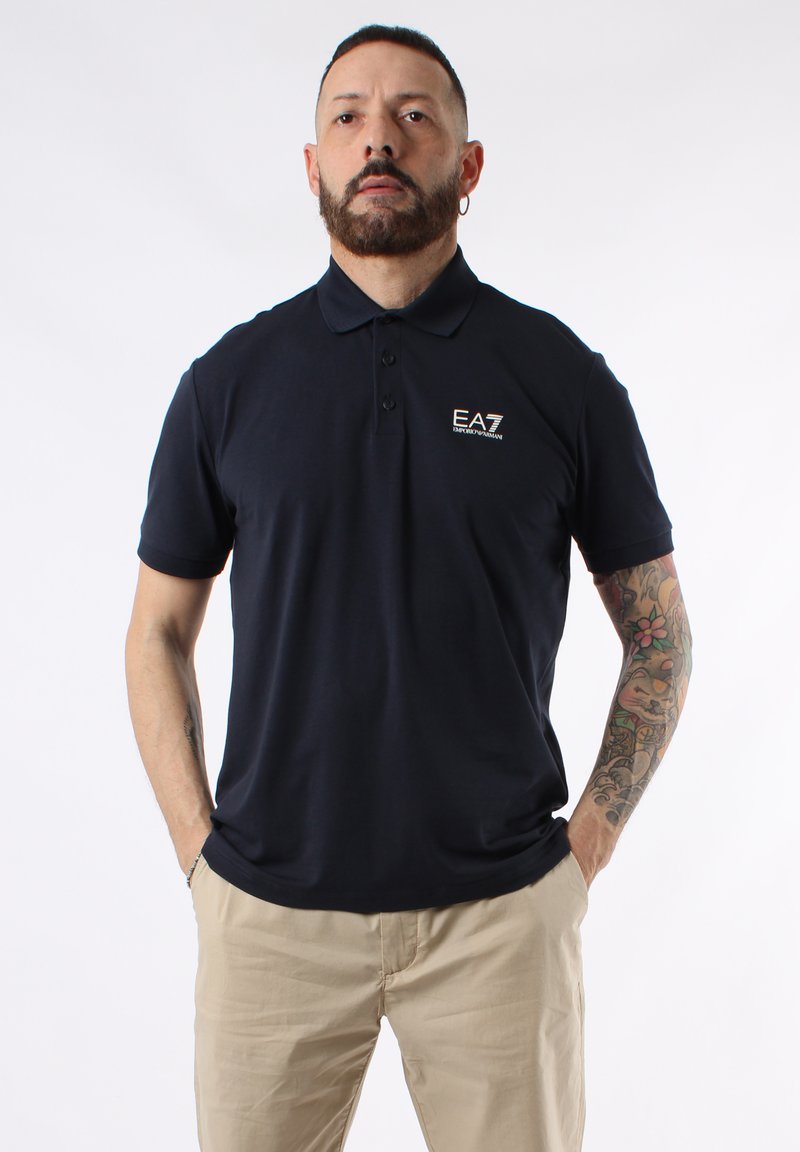 Polo navy de algodón con cuello, manga corta, tapeta de tres botones y logo de EA7 en el lado izquierdo del pecho.