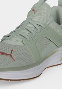 Ανοιχτό πράσινο αθλητικό παπούτσι Puma με επάνω μέρος από δίχτυ, κλείσιμο με κορδόνια, ενισχυμένη σόλα και κόκκινο λογότυπο Puma στο μπροστινό μέρος και στη γλώσσα.