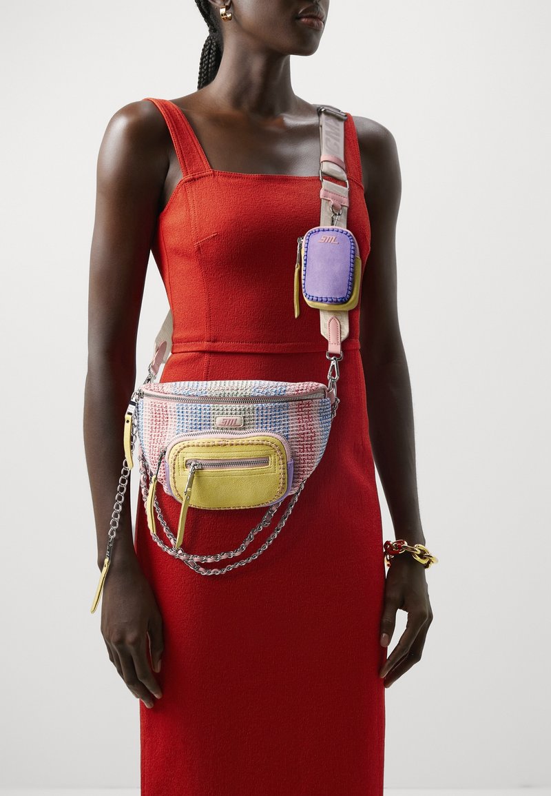 Multifunctionele handtas met geweven textiel in pastelkleuren, voorzien van gele en paarse accenten en zilveren kettinghardware.